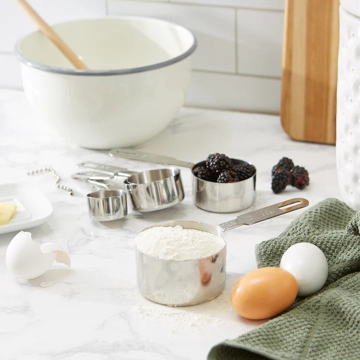 An RSVP Endurance Measuring Cups, Set of 5 on marble countertop, alongside other baking tools and ingredients.