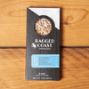 One Ragged Coast Chocolates Chocolate Almond and Maine Sea Salt Bark sits on a wooden table.