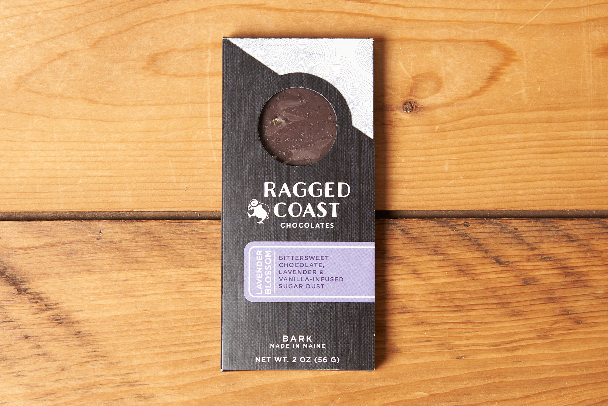 One Ragged Coast Chocolates Chocolate Lavender Blossom Bark sits on a wooden table.