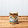 A jar of Raye's Brown Ginger Mustard sits on a brown wooden table.