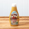 A bottle of Raye's Downeast Schooner Mustard sits on a brown wooden table.