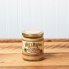 A jar of Raye's Maple Horseradish Mustard sits on a brown wooden table.