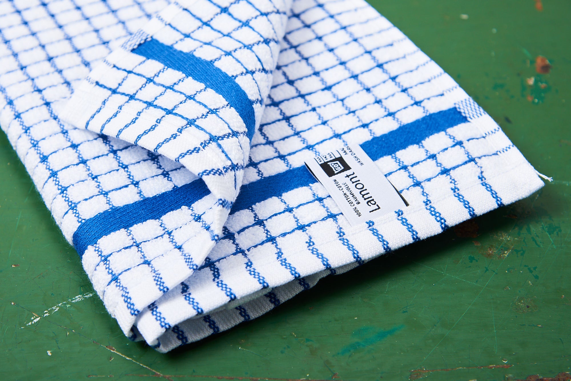 A blue Samuel Lamont Poli-Dry Towel sits on a green wooden tabletop.