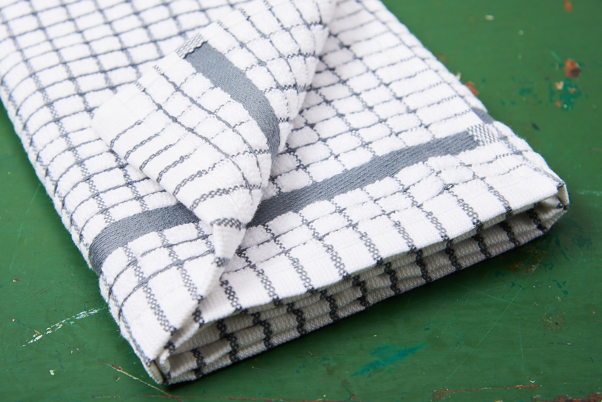 A grey Samuel Lamont Poli-Dry Towel sits on a green wooden tabletop.