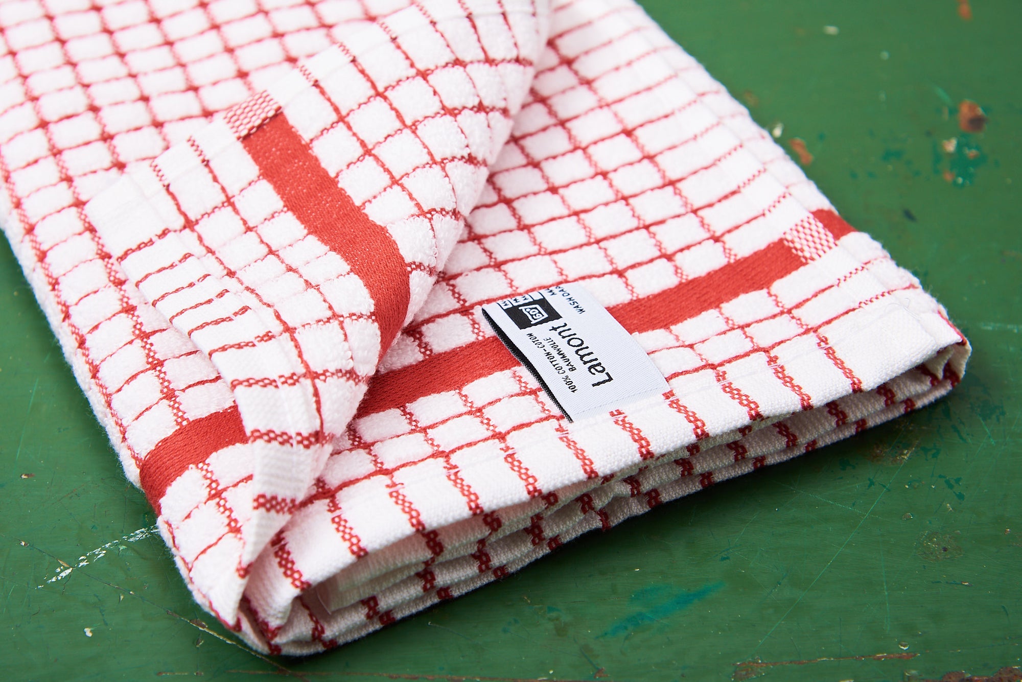 A red Samuel Lamont Poli-Dry Towel sits on a green wooden tabletop.
