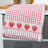 A red Samuel Lamont Poli-Dry Towel with woven strawberries drapes over a counter.