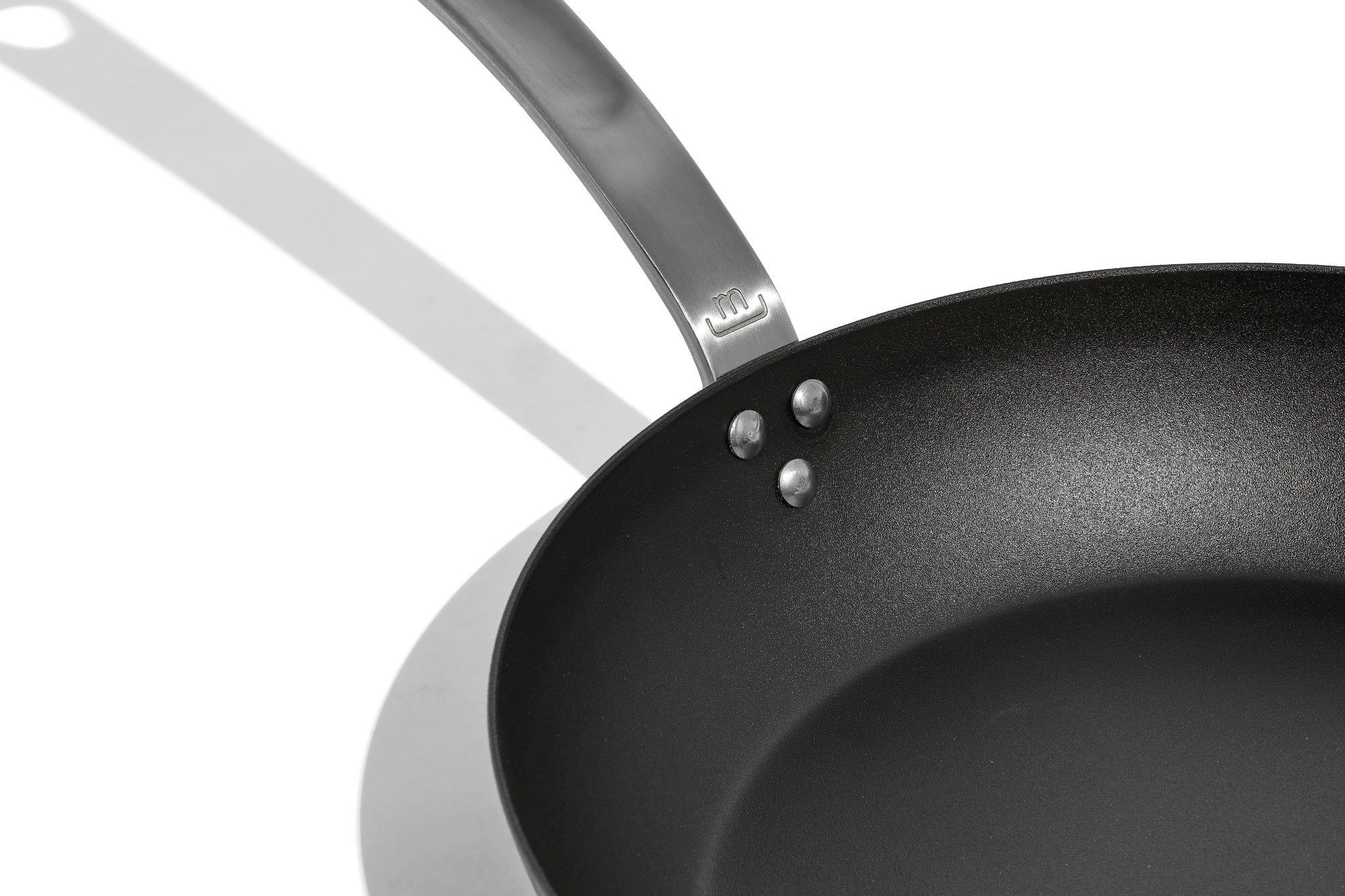 A close up shot of a Made In Seasoned Carbon Steel Fry Pan over a white background.