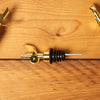 Gold Self Closing Weighted Pour Spouts sit on a wooden table.