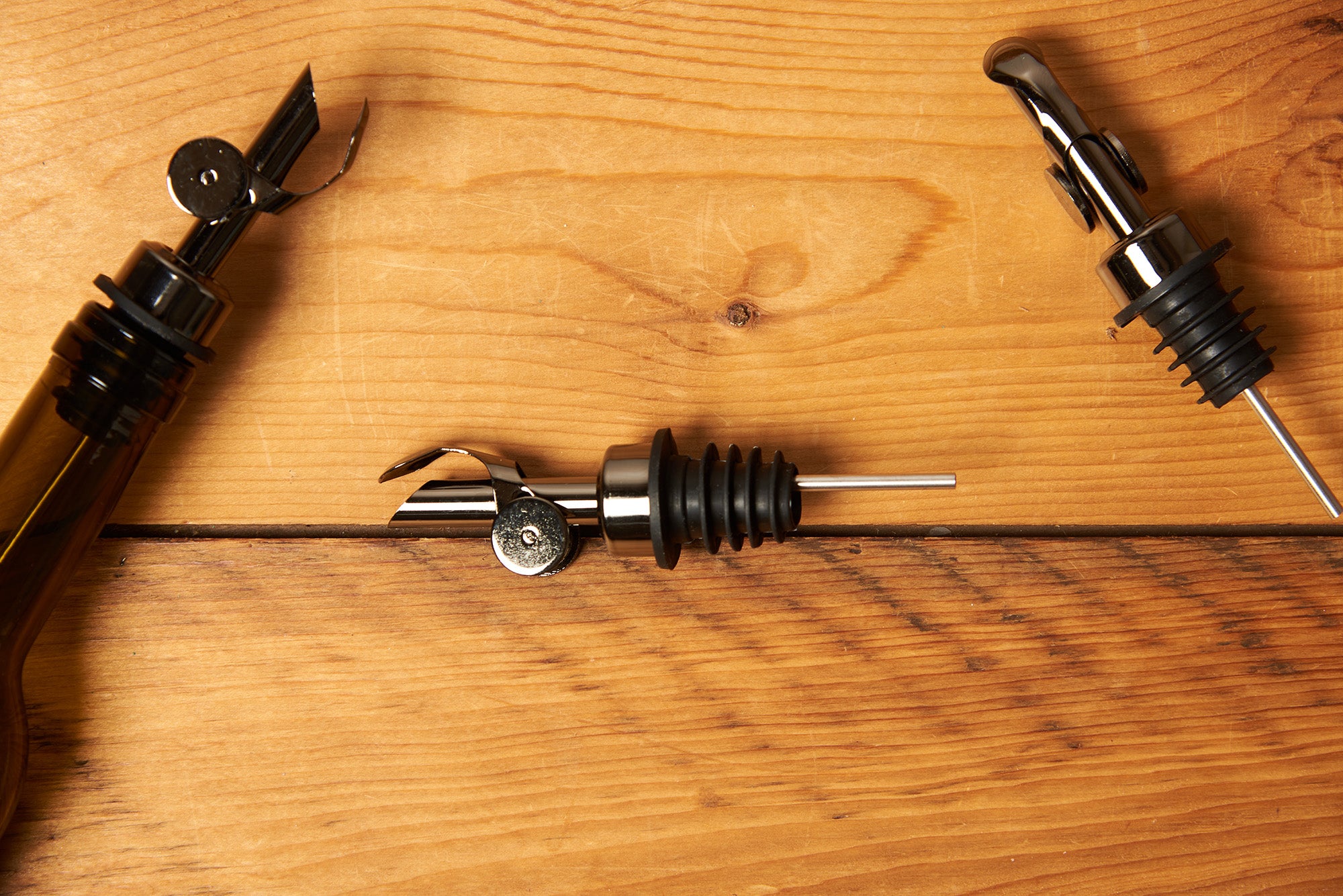 Black Self Closing Weighted Pour Spouts sit on a wooden table.