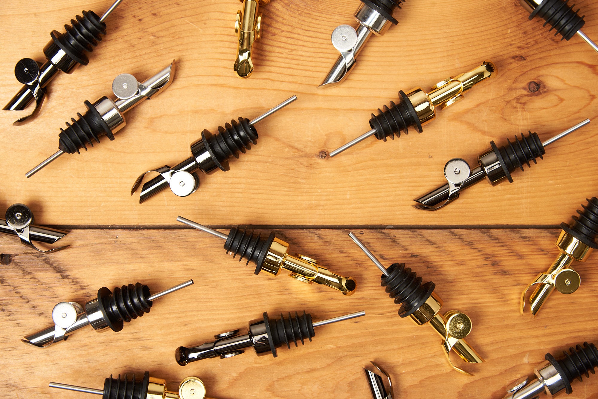 Many Self Closing Weighted Pour Spouts are scattered across a wooden table.