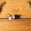 Silver Self Closing Weighted Pour Spouts sit on a wooden table.