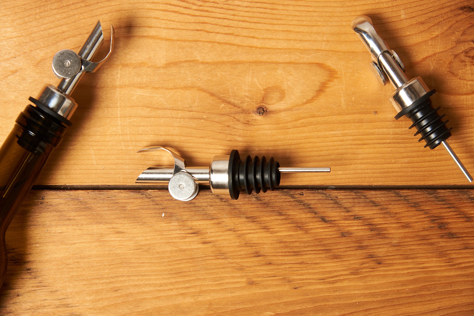 Silver Self Closing Weighted Pour Spouts sit on a wooden table.