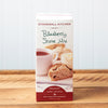 A box of Stonewall Kitchen Blueberry Scone Mix sits on a brown wooden table.