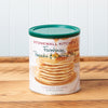 A canister of Stonewall Kitchen Farmhouse Pancake & Waffle Mix sits on a brown wooden table.