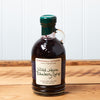 A bottle of Stonewall Kitchen Wild Maine Blueberry Syrup sits on a brown wooden table.