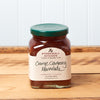 A jar of Stonewall Kitchen Orange Cranberry Marmalade sits on a brown wooden table.