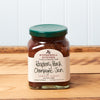 A jar of Stonewall Kitchen Raspberry Peach Champagne Jam sits on a brown wooden table.