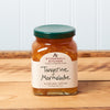 A jar of Stonewall Kitchen Tangerine Marmalade sits on a brown wooden table.