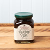 A jar of Stonewall Kitchen Fig & Ginger Jam sits on a brown wooden table.