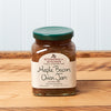 A jar of Stonewall Kitchen Maple Bacon Onion Jam sits on a brown wooden table.