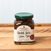 A jar of Stonewall Kitchen Roasted Garlic Onion Jam sits on a brown wooden table.