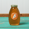 A jar of Swan's Orange Blossom Honey sits on a turquoise wooden table.