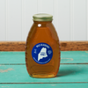 A jar of Swan's Wild Blueberry Honey sits on a turquoise wooden table.
