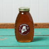 A jar of Swan's Raspberry Honey sits on a turquoise wooden table.