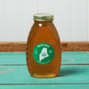 A jar of Swan's Wildflower Honey sits on a turquoise wooden table.