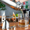 A cocktail is poured from a cocktail shaker into a rocks glass.