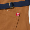 A close up shot of a Hedley & Bennett Denver brown Essential Apron over a white background.
