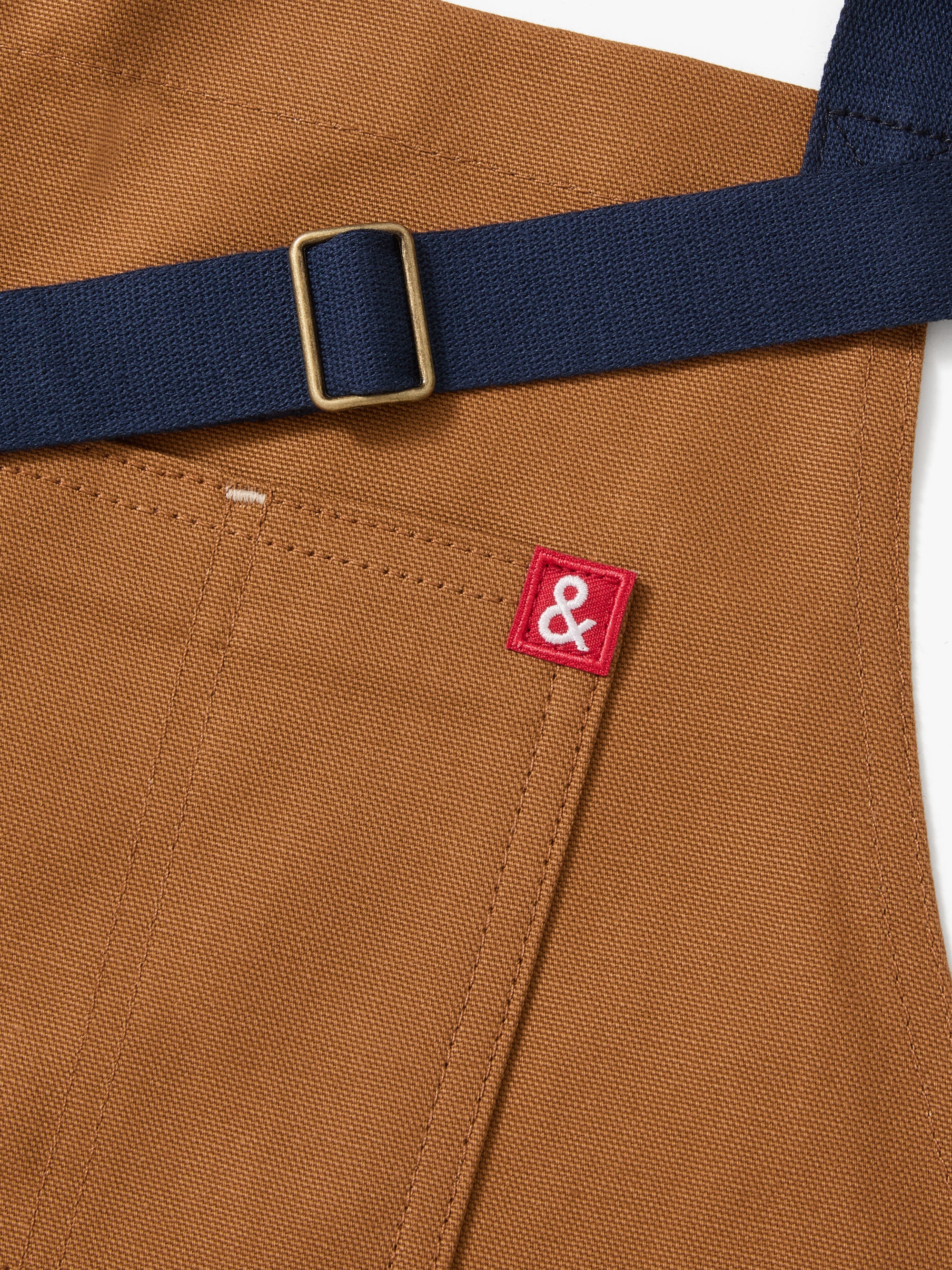 A close up shot of a Hedley & Bennett Denver brown Essential Apron over a white background.
