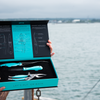 The Toadfish Coastal Kitchen Collection in its box is held in front of the ocean.