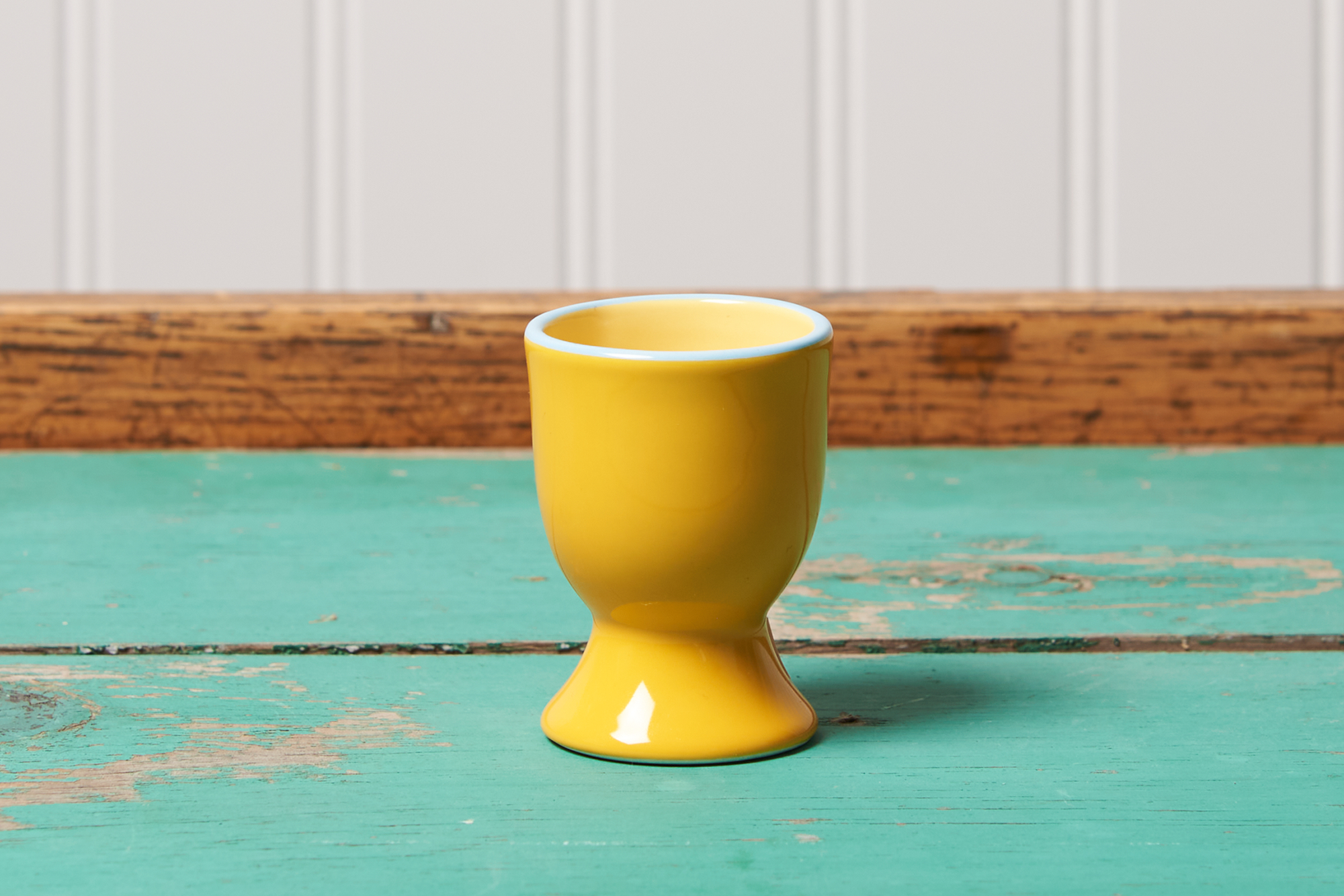 A yellow Tranquillo Egg Cup sits on a turquoise table.