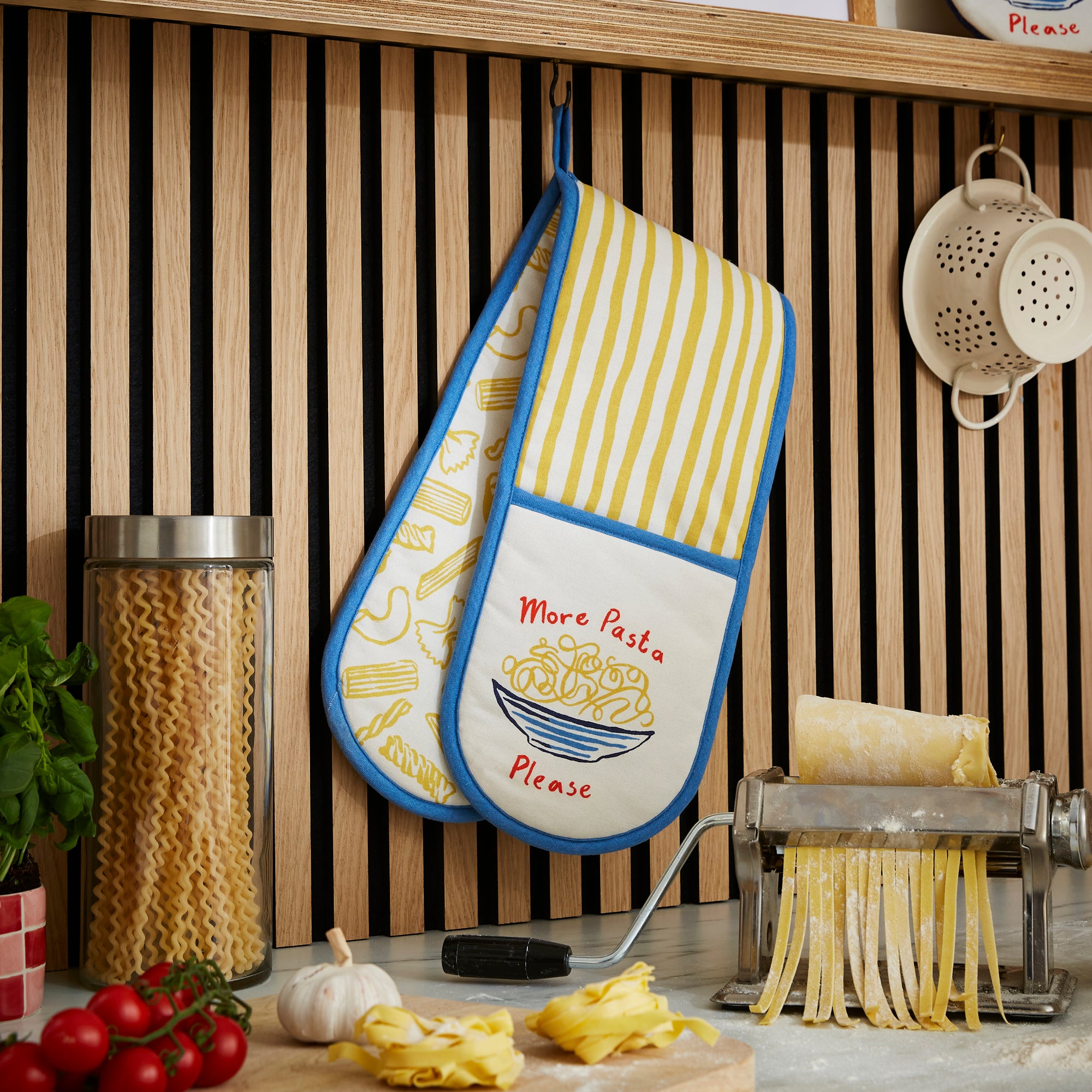 An Ulster Weavers Double Oven Mitt in the Pasta Lovers Club pattern hangs over a kitchen countertop.