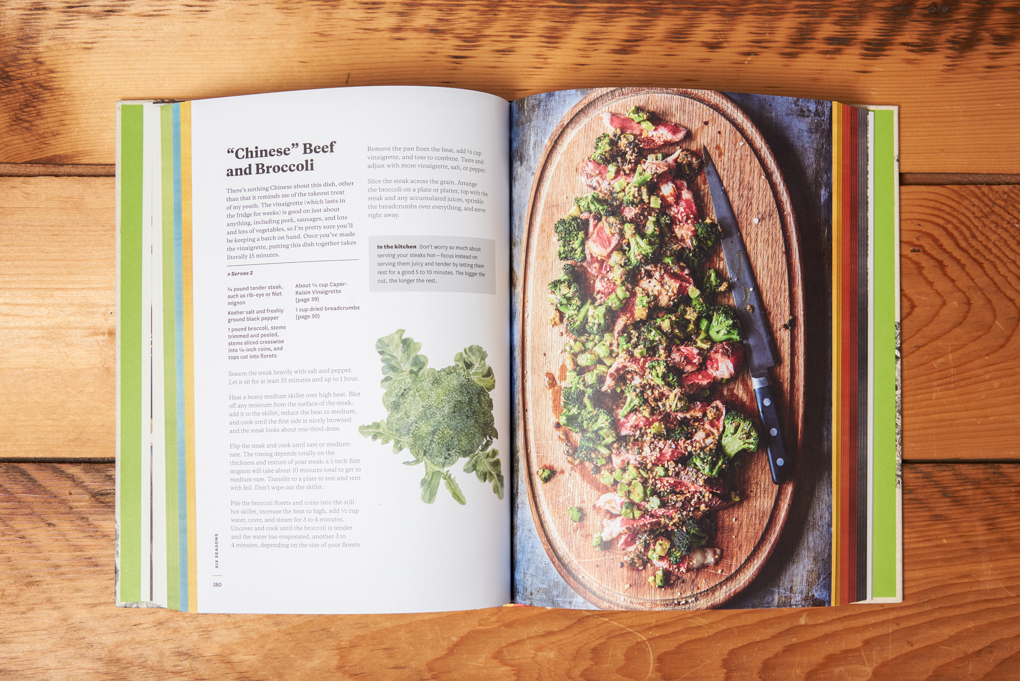The cookbook 'Six Seasons: A New Way with Vegetables' sits open on a wooden table. The open page is a recipe and photo for "Chinese" Beef and Broccoli.
