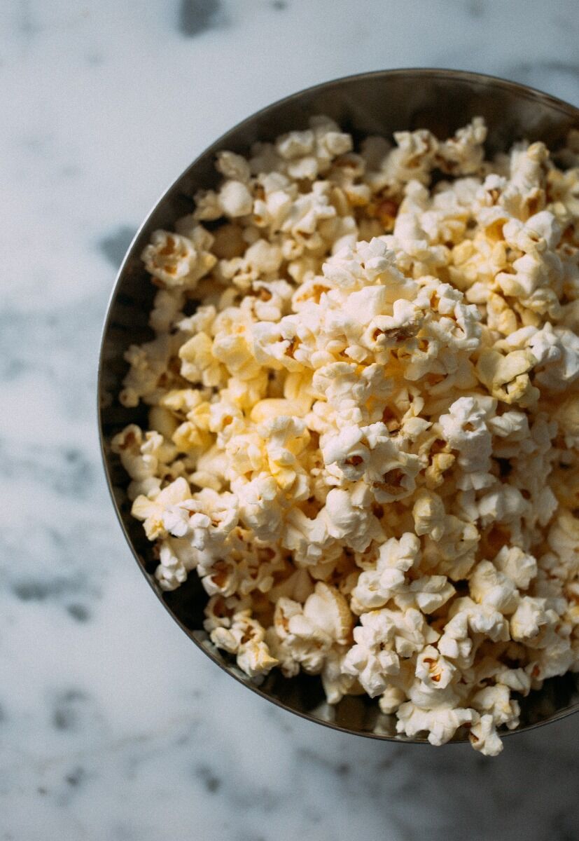 Close-up of buttery popcorn in a metal bowl on a marble surface