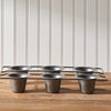 Six muffin cups in a tray on wooden surface with striped background