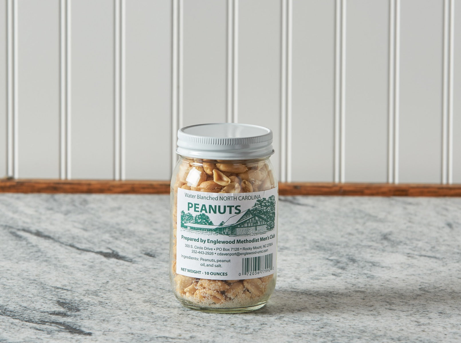 Jar of North Carolina water blanched peanuts on marble counter.
