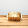 Gold fluted pillow design cushion on wooden surface against blue wall