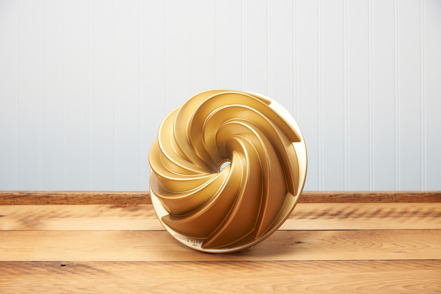 Golden spiral sculpture on a wooden table against a blue wall