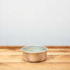Copper pet bowl on wooden floor against a blue wall background