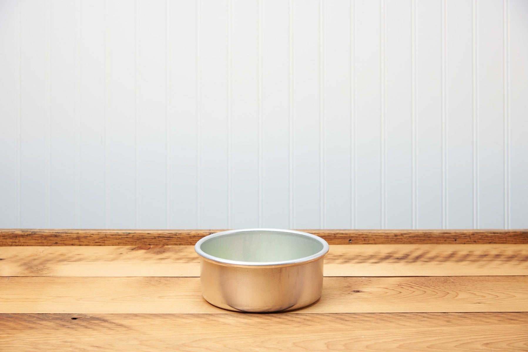 Copper pet bowl on wooden floor against a blue wall background