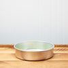 Empty metal sieve on a wooden table against a white background