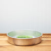 Round copper cake pan on wooden countertop with pack of baking mix inside
