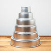 Silver tiered round cake stand on a wooden table against a white beadboard background