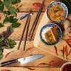 Japanese cuisine with sushi, rice bowl, fresh herbs, ginger, and chili on wooden surface