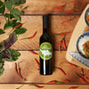 Bottle of LeRoux olive oil on wooden table with chili peppers and Asian food.