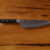 Chef's knife with serrated edge on wooden background