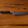 Damascus steel chef knife with dark handle on wooden background